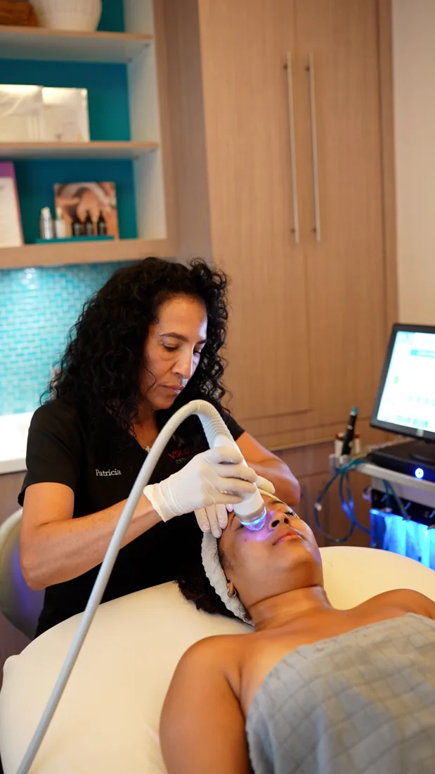 A clinician using a treatment device during facial care