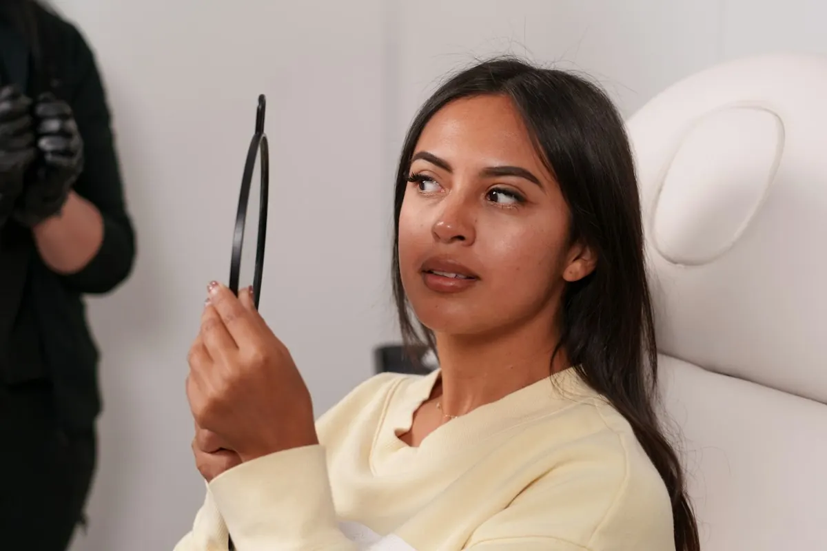 A client reviewing her features in a hand mirror