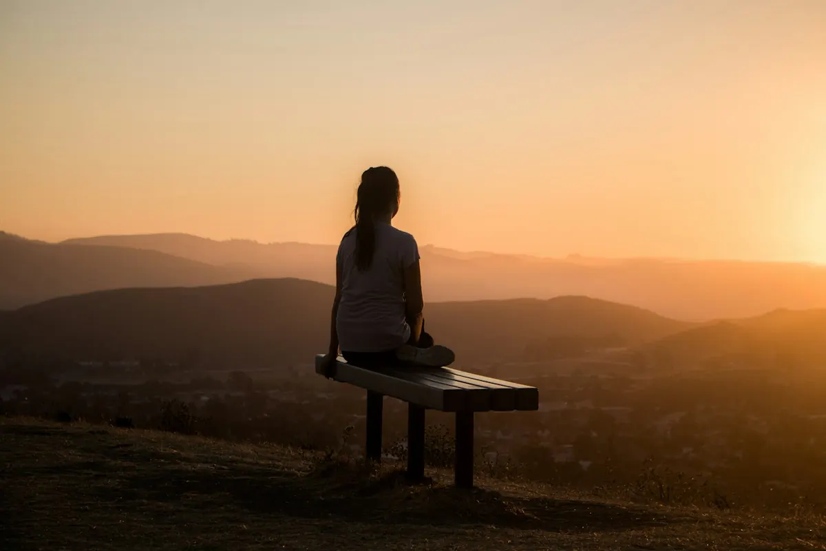 A woman sitting alone looking out over the hills